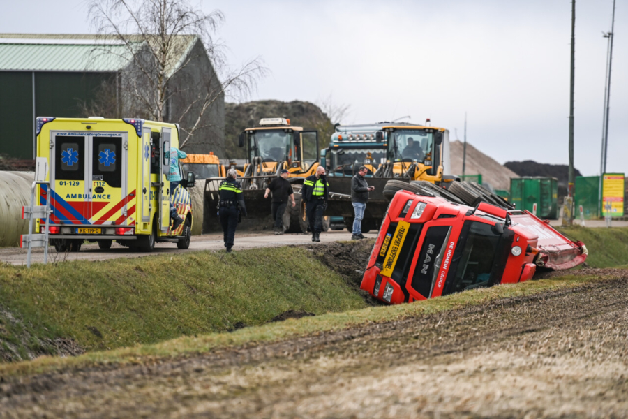 Vrachtwagen belandt op zijkant in greppel, chauffeur niet gewond