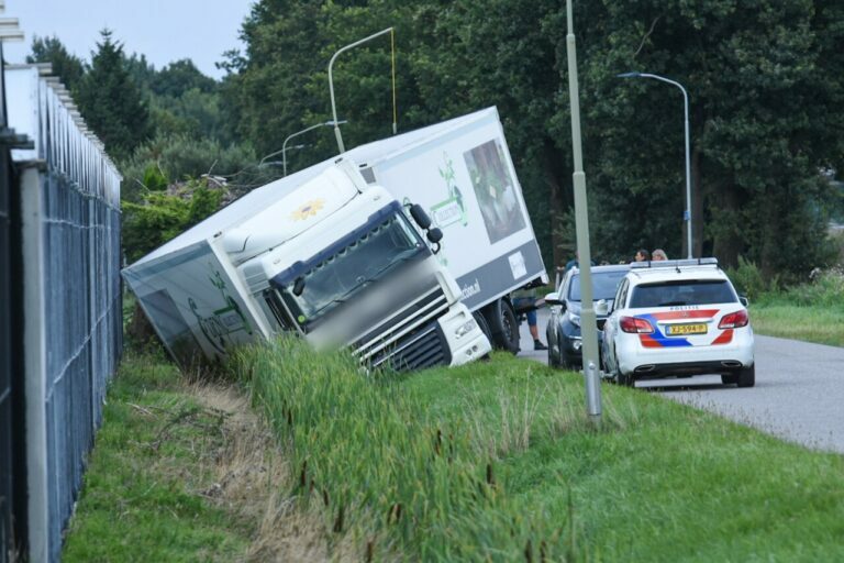 Vrachtwagen combinatie ramt lantaarnpaal, komt in sloot terecht en kantelt tegen kas aan in Klazienaveen