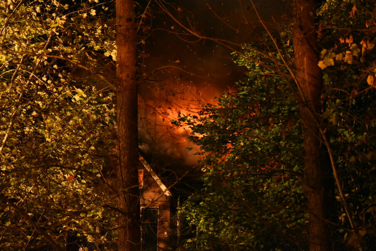 Vlammen slaan uit dak gebouw in Wilhelminaoord