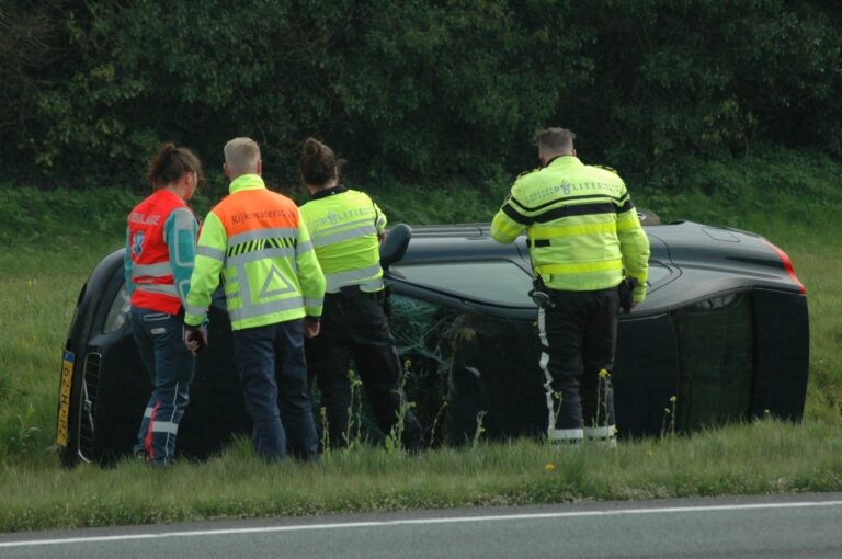 Auto raakt van de weg en komt op de zijkant tot stilstand, bestuurder naar ziekenhuis