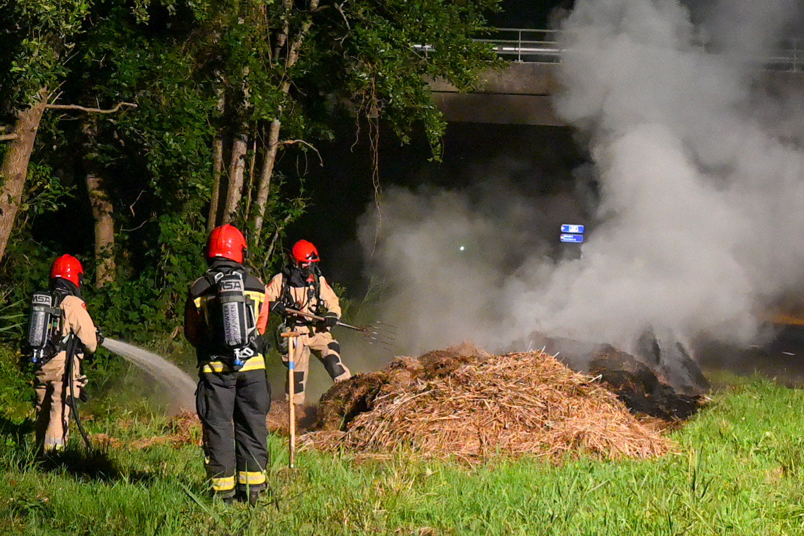 Brandweer druk bezig met brandende bult gemaaid gras