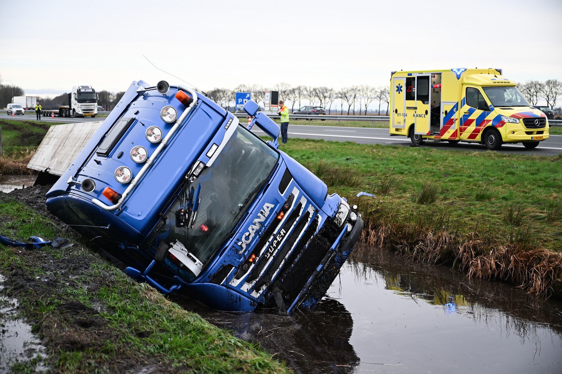 Vrachtwagen in sloot langs snelweg, rijstrook uren dicht