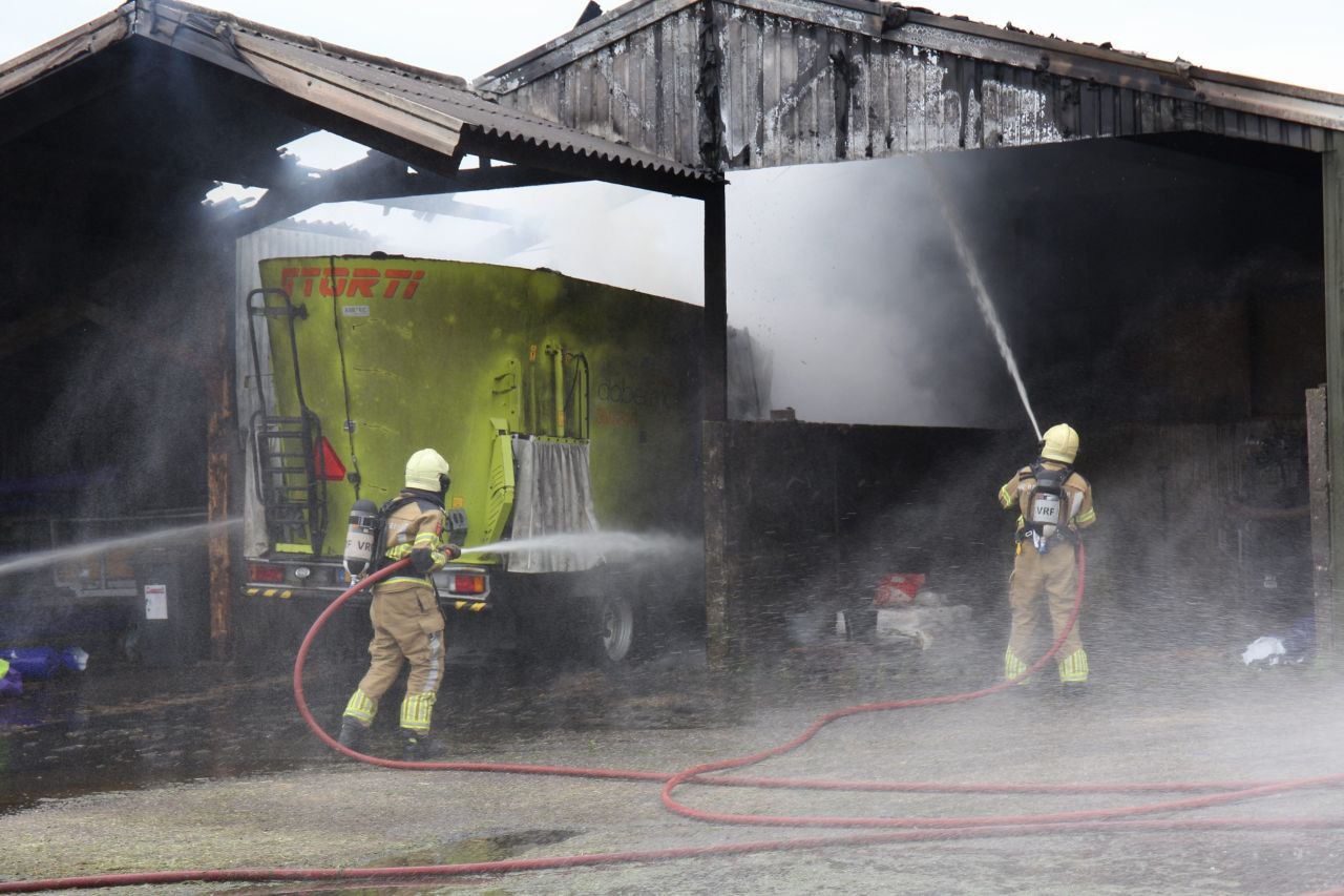 Voermengmachine vliegt in brand onder afdak, brandweer schaalt op naar grote brand