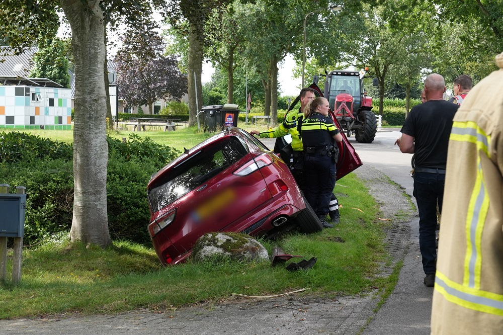 Auto ramt grote steen en belandt in sloot