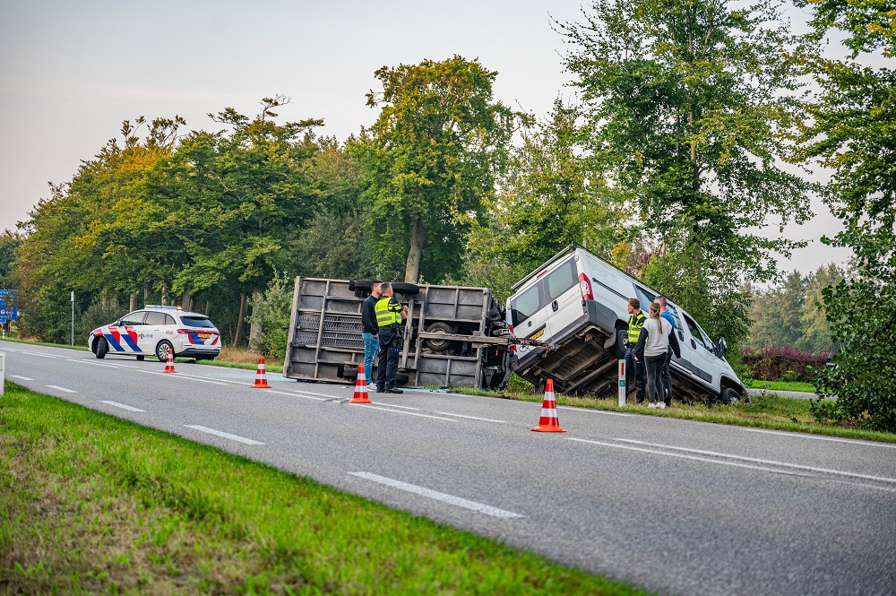 Busje met aanhanger vliegt over de kop