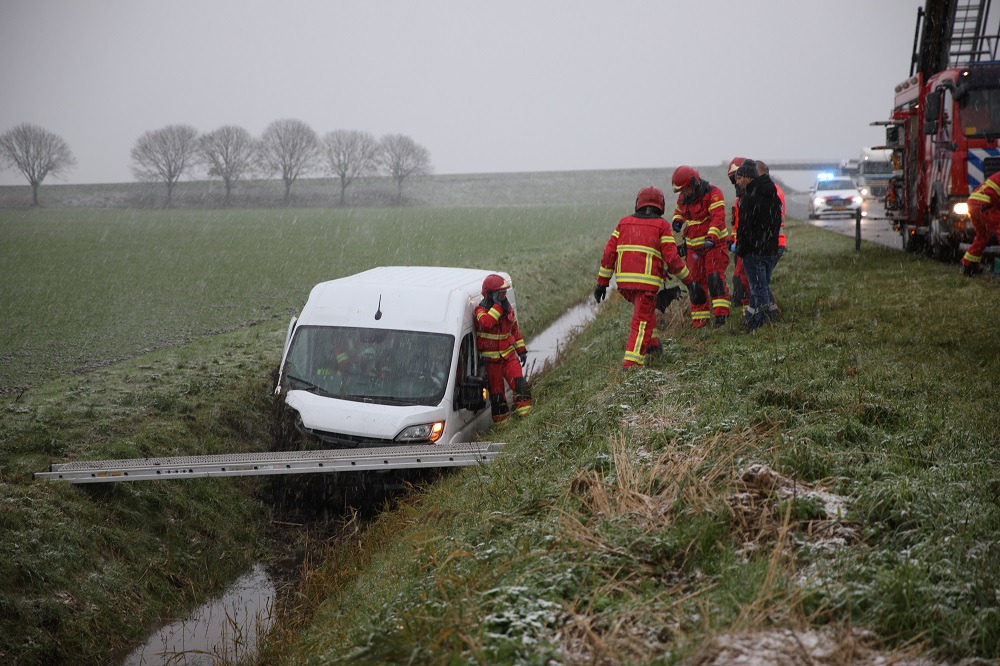 Bestelbus raakt van de weg tijdens sneeuwbui, bestuurder gewond