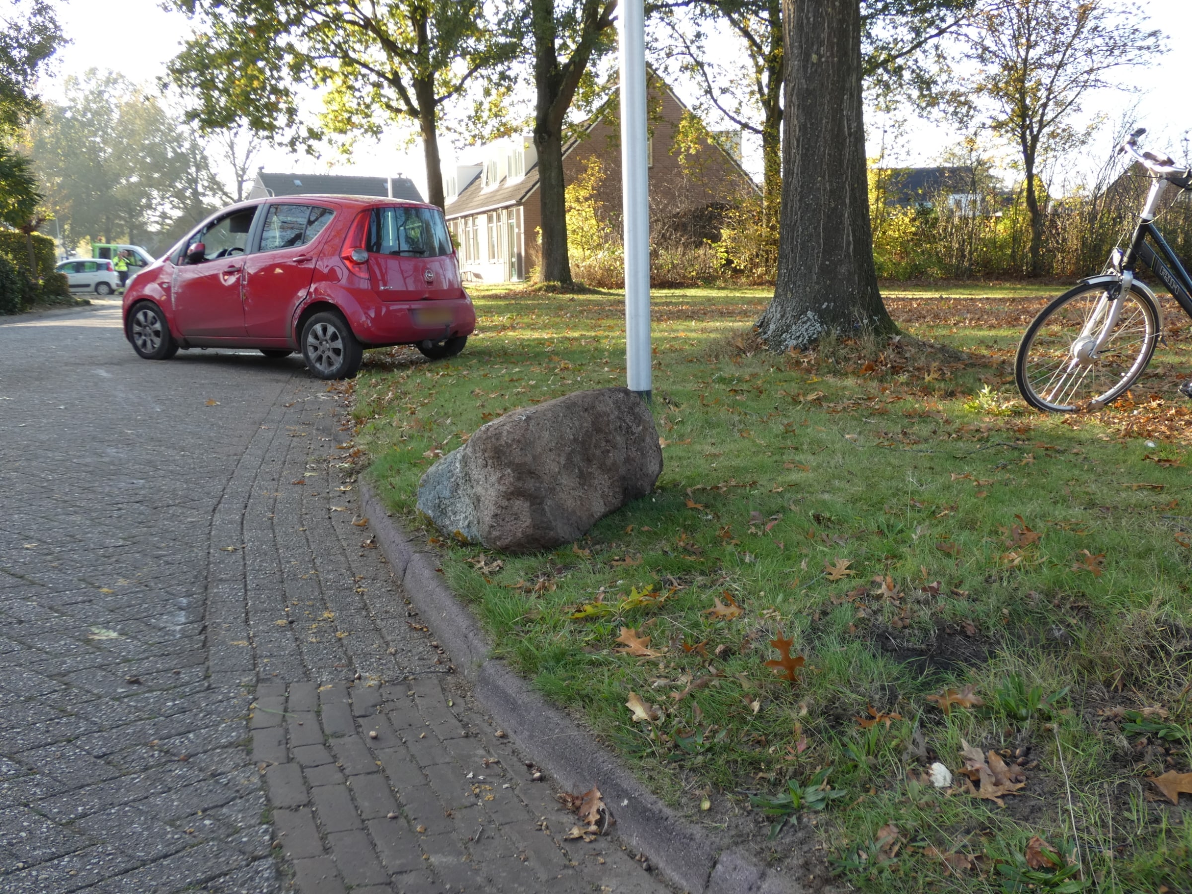 Auto belandt op zijkant na botsing tegen kei langs de weg