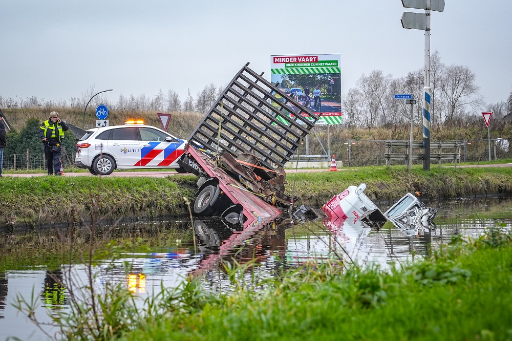Aanhanger met graafmachine raakt los van tractor en rijdt water in