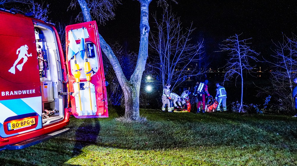 Oudere vrouw met auto te water, omstander schiet te hulp