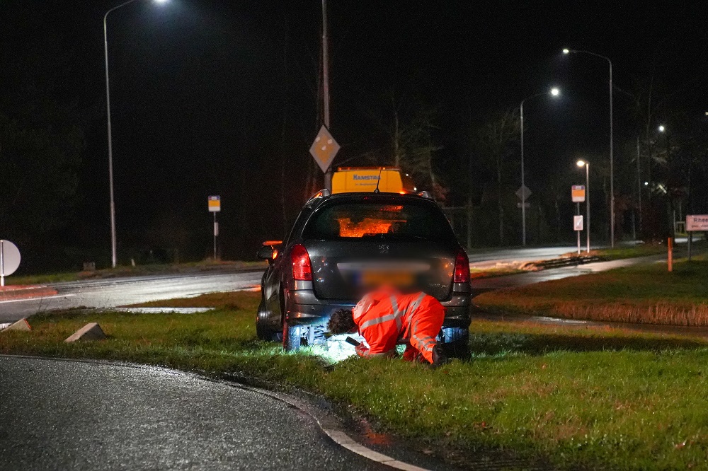 Auto van de weg op rotonde en raakt beton blok