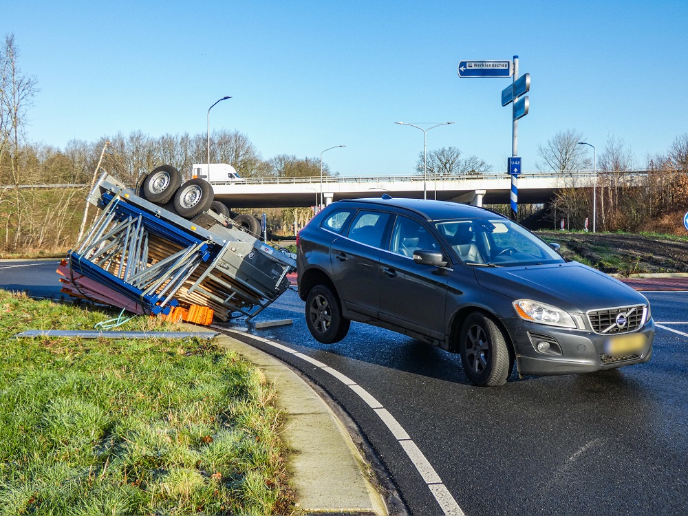 Aanhanger achter auto op z’n kop op rotonde