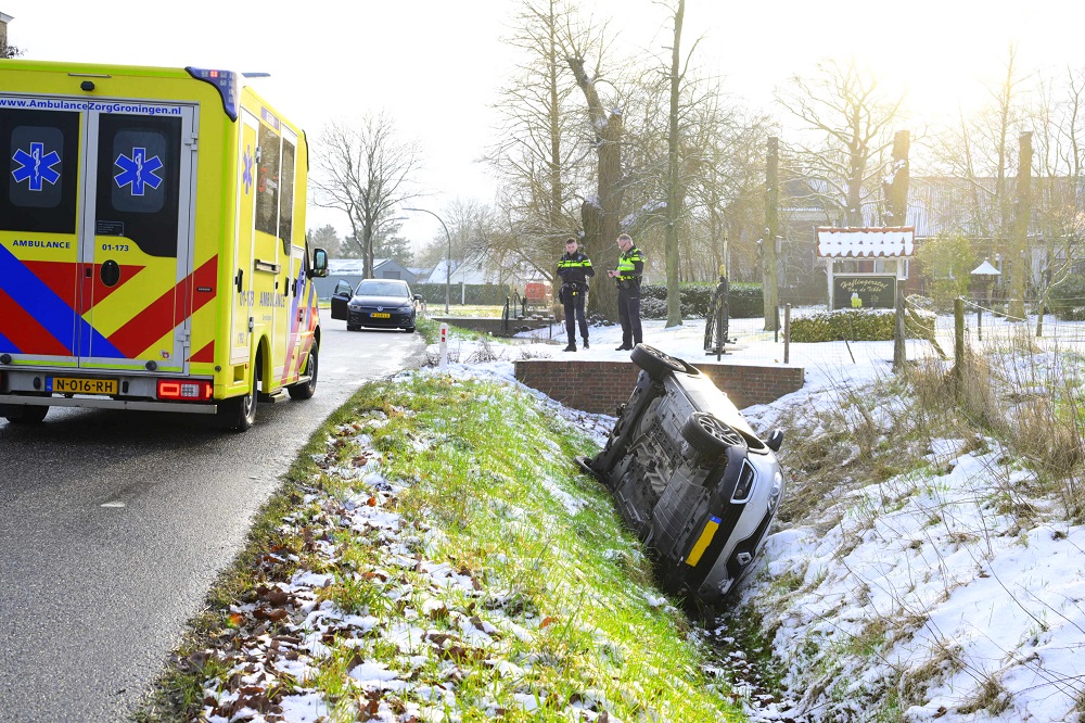 Auto op zijn kant in greppel