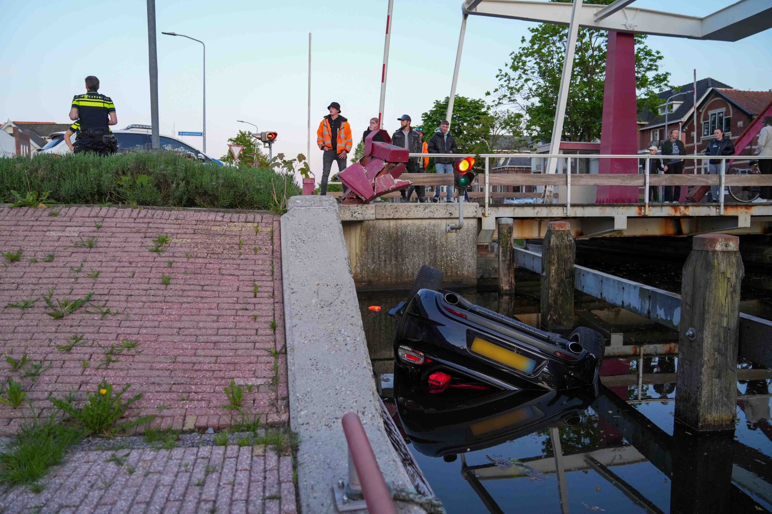 Auto belandt ondersteboven in kanaal, bestuurder naar ziekenhuis