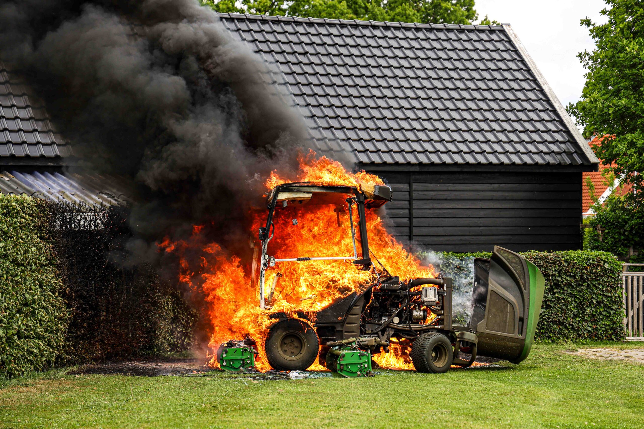 Grasmaaier vat vlam op sportveld, brandweer blust met schuim