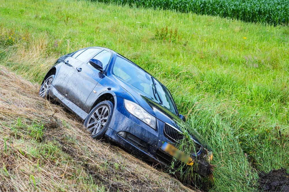 Auto raakt tijdens hevige regenbui van de weg