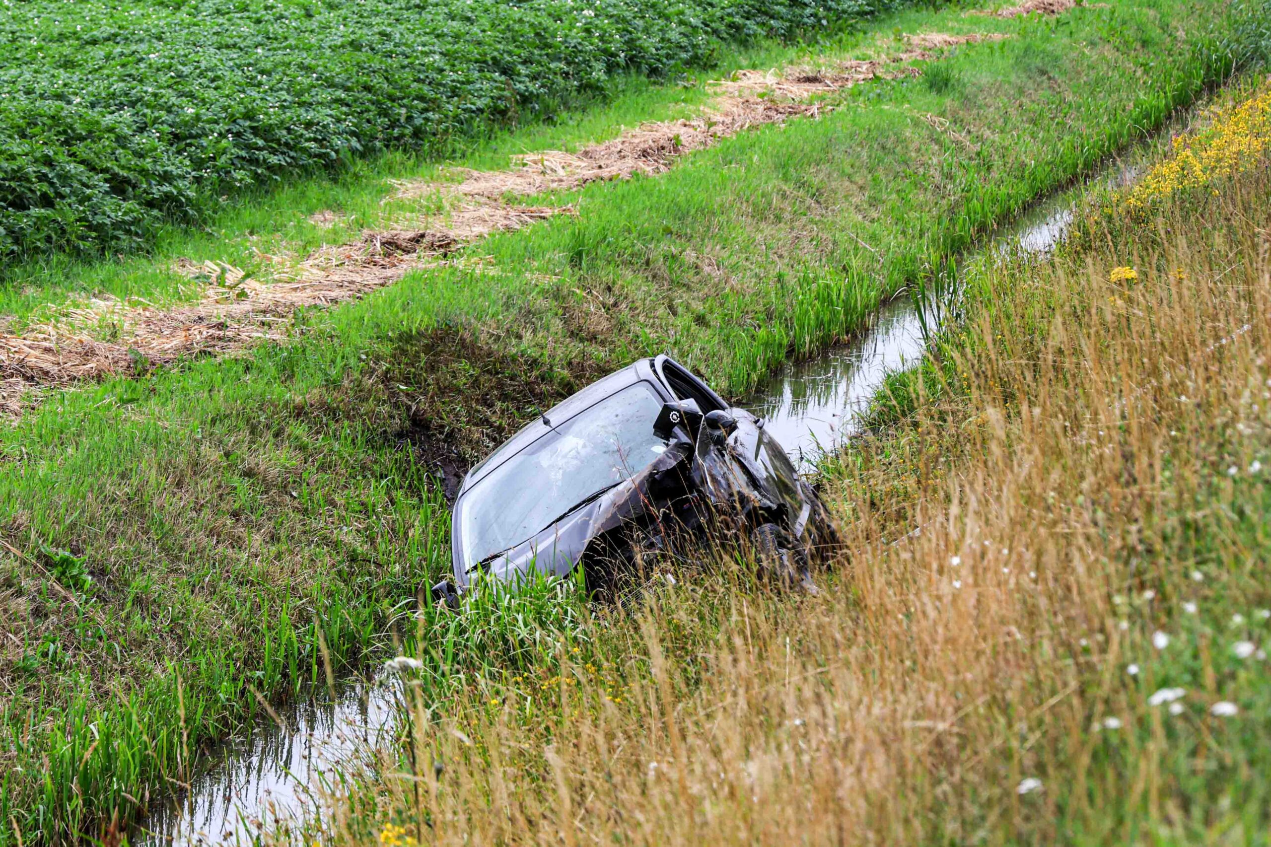 Auto belandt in sloot, bestuurder bekneld geraakt