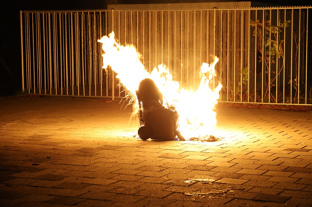 Afvalcontainer in brand midden op schoolplein