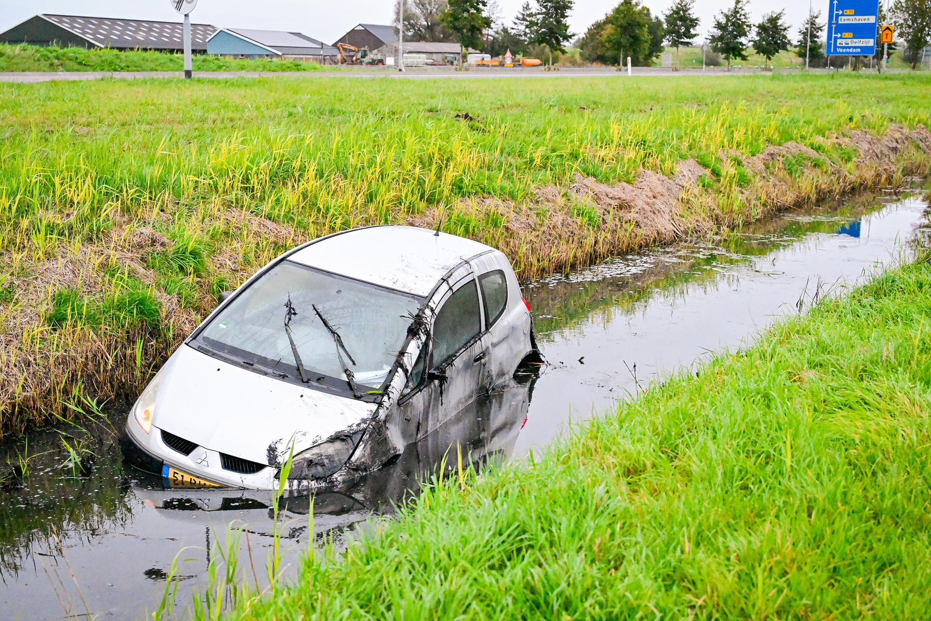 Auto belandt in sloot bij N-weg, bestuurder onderzocht door ambulancepersoneel