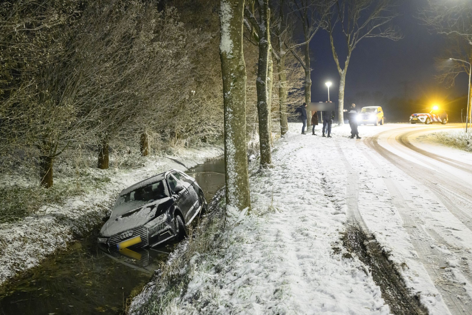Auto glijdt door winterse neerslag de sloot in