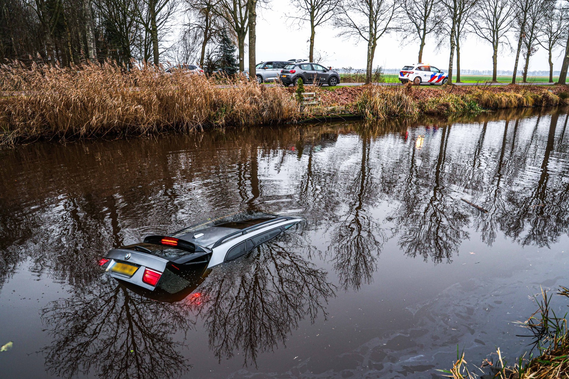 Auto rijdt kanaal in, inzittenden zwemmen naar de kant