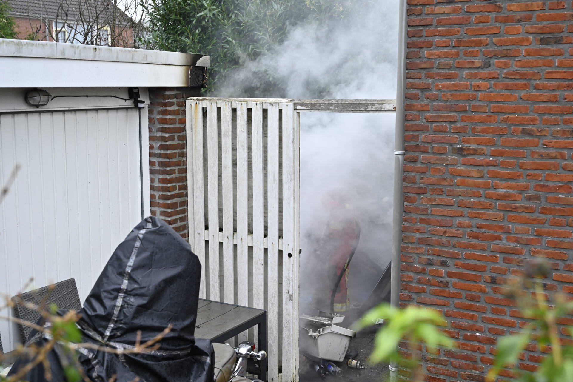 Brand in afvalstapel achter woning, naastgelegen garage beschadigd