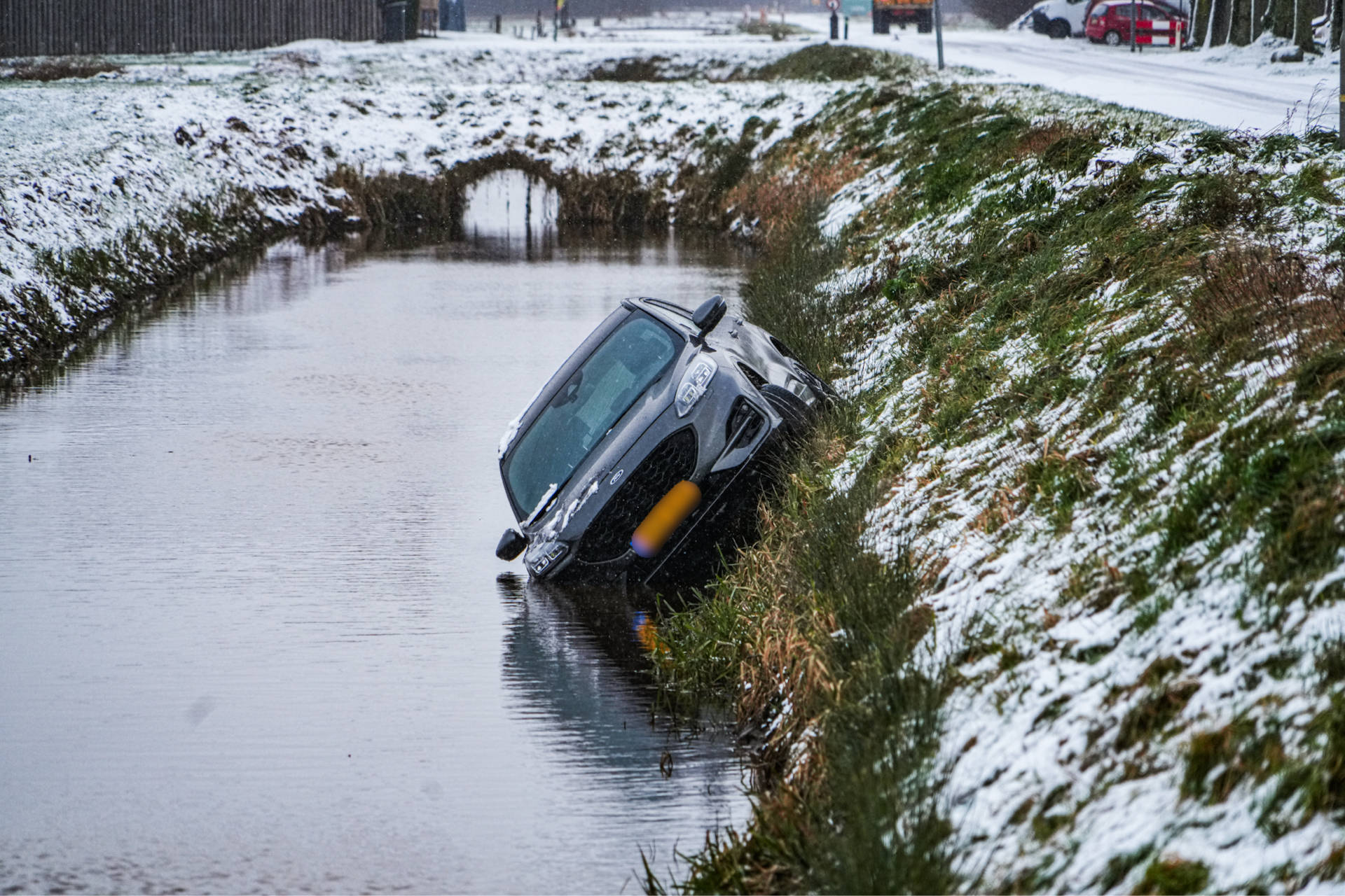 Auto glijdt door sneeuw en belandt in sloot