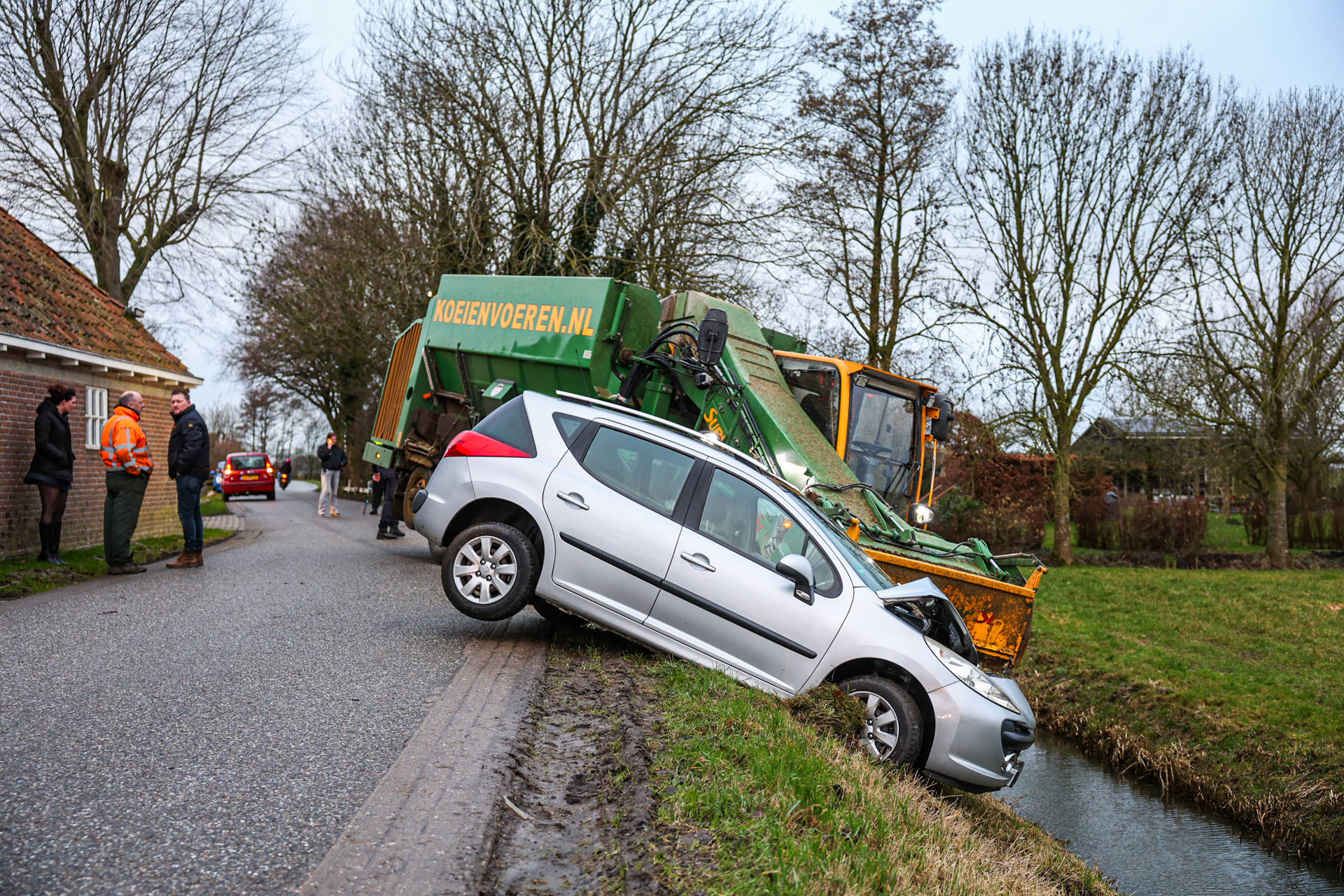 Voermengwagen en auto belanden bijna in sloot na botsing