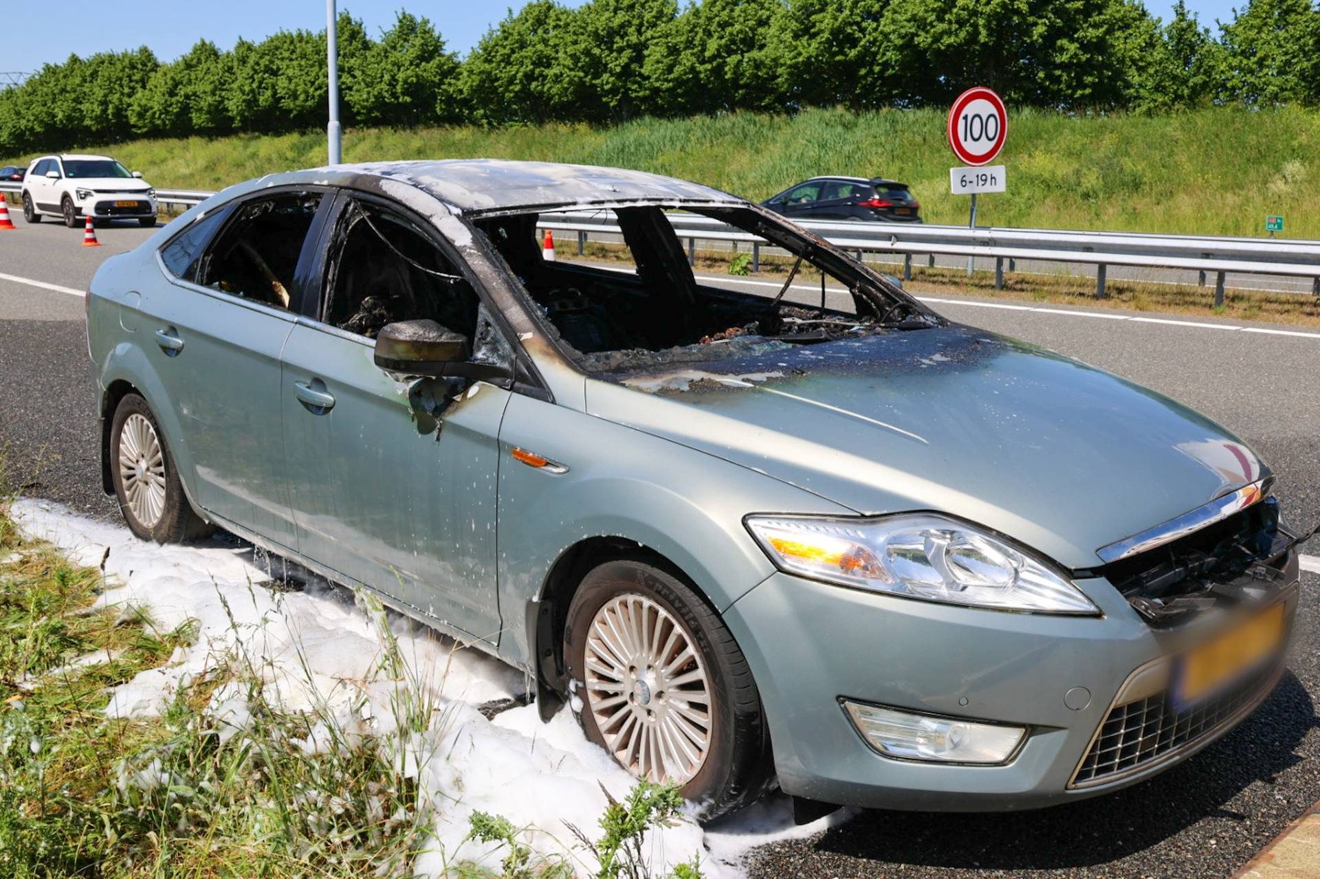 Auto brandt uit langs snelweg, bestuurder gewond