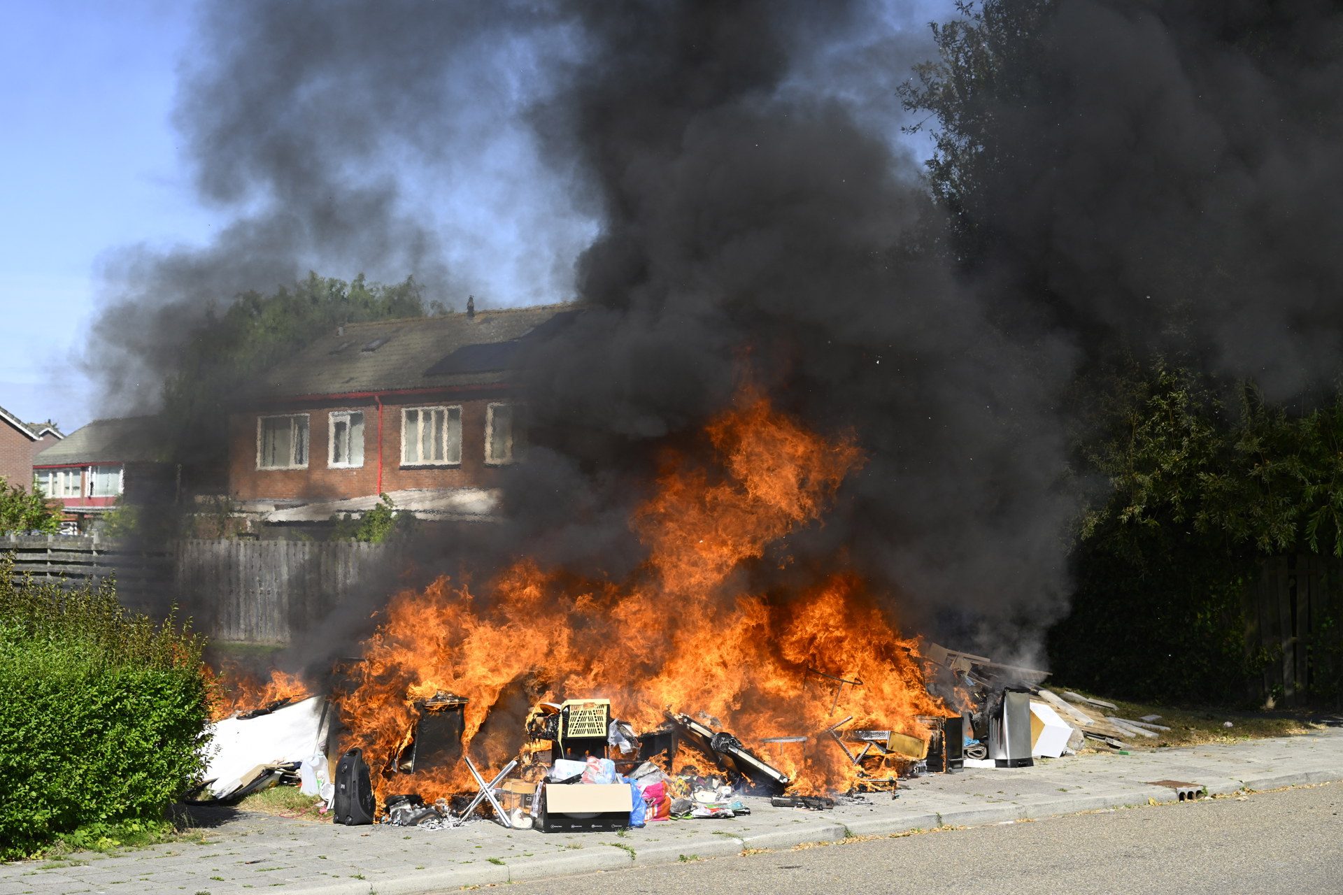 Grote afvalbult vliegt in brand, ramen van naastgelegen woning springen eruit