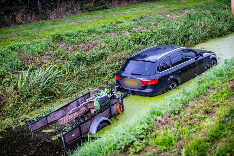 Auto en aanhanger met motor eindigen in sloot