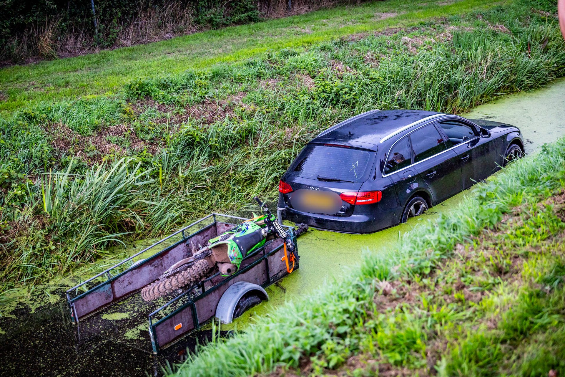 Auto en aanhanger met motor eindigen in sloot