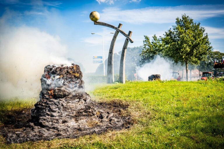 Boeren verzamelen zich met trekkers, hooibalen in brand
