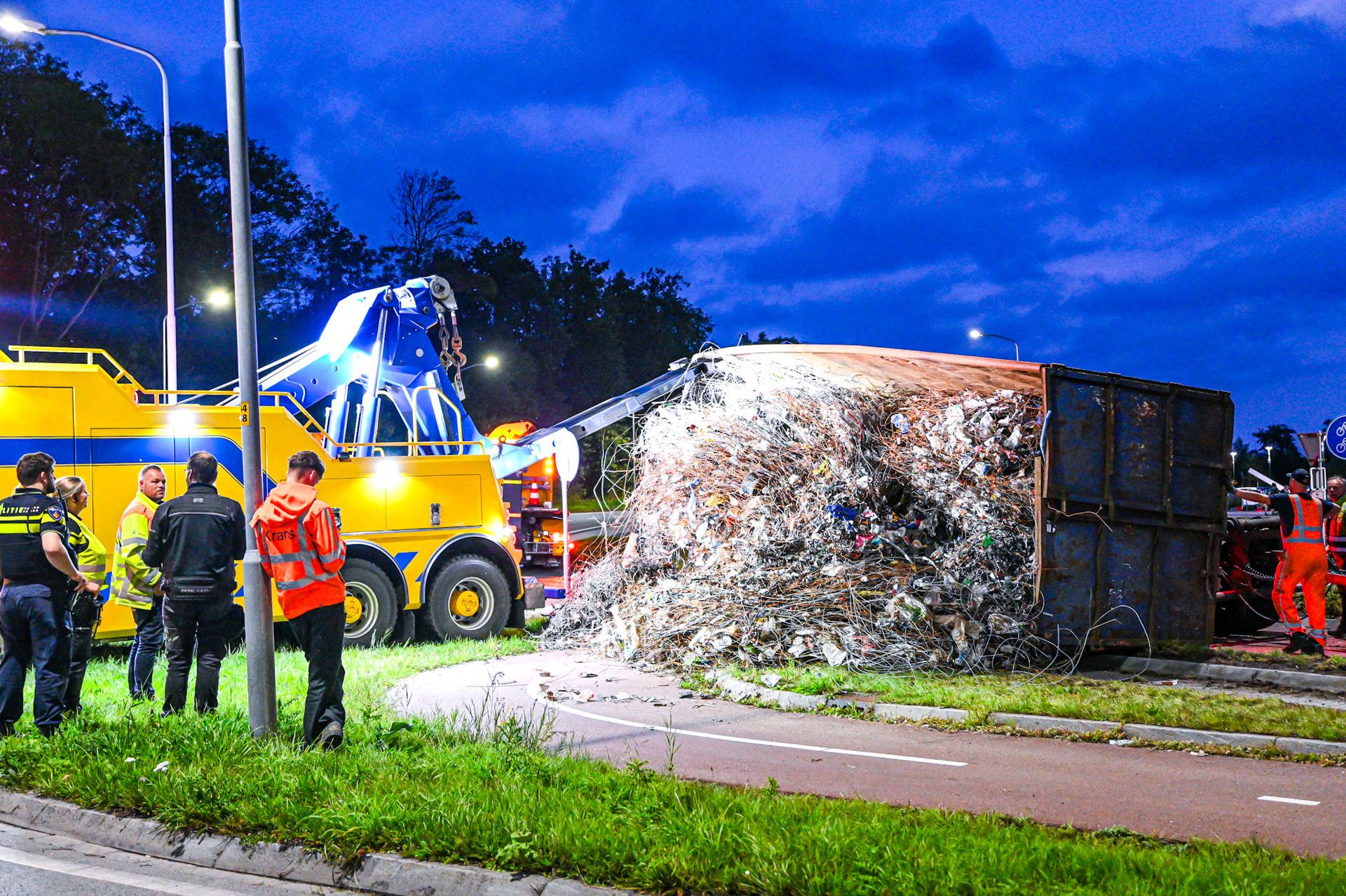Container met oud ijzer valt van vrachtwagen en veroorzaakt flinke ravage